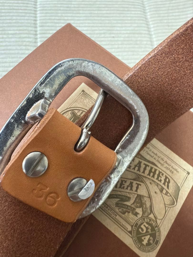 ダルチザンのご神体とアベニューコタローの刻印入りの、シンプルなバックルのベルト