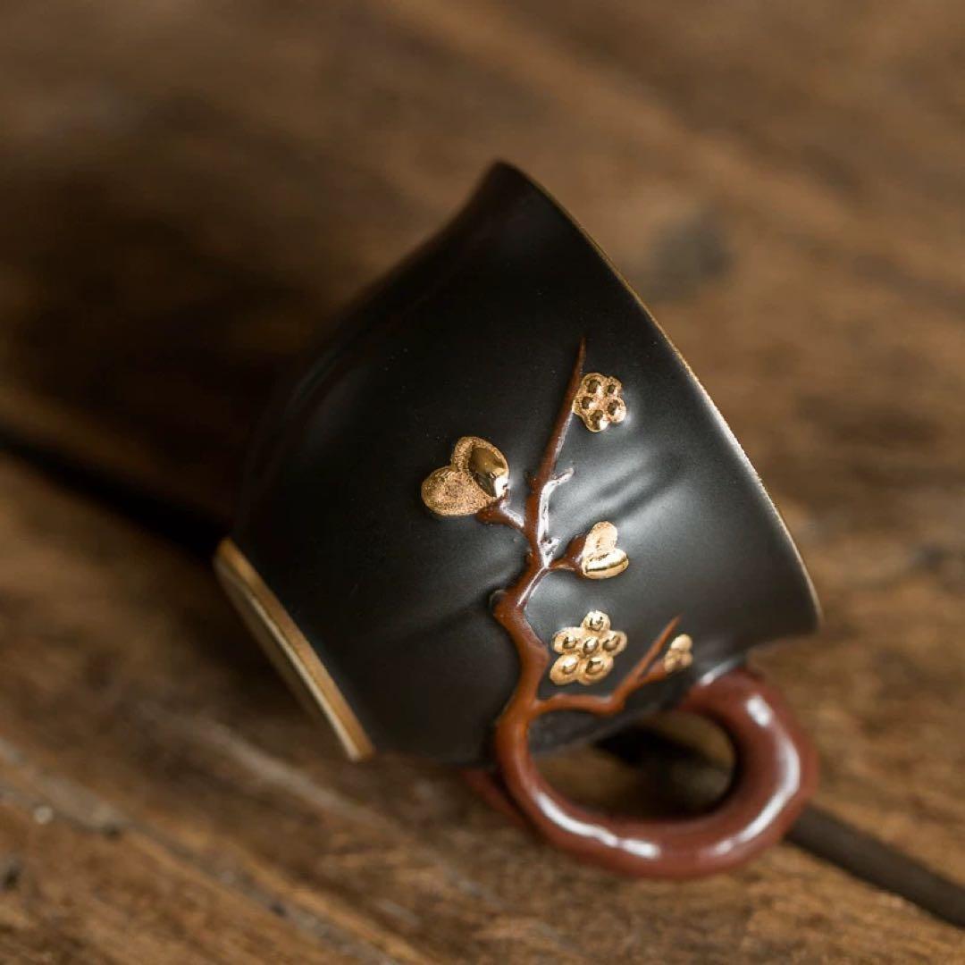 黒い陶器のカップ 金色の花模様