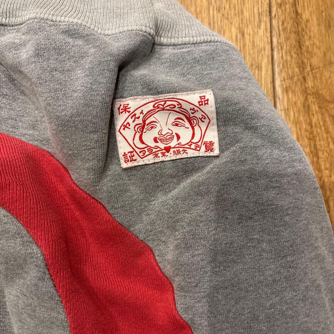 グレー スウェットパンツ 赤いパッチ 金色ロゴ