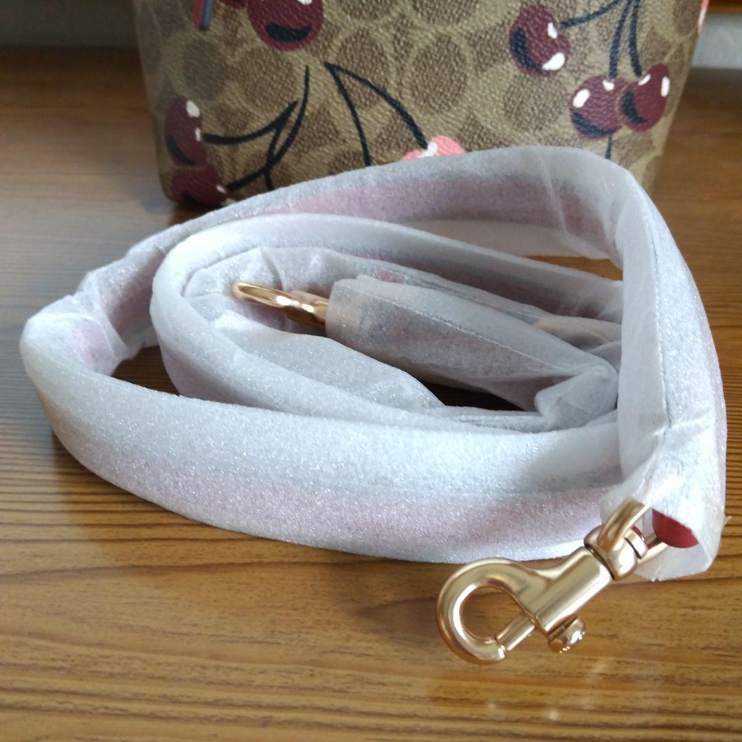 クリーム。COACHチェリー柄トートバッグ、ショルダーストラップ付き。