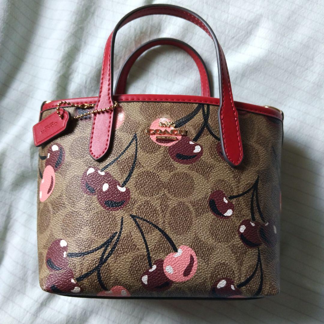 クリーム。COACHチェリー柄トートバッグ、ショルダーストラップ付き。