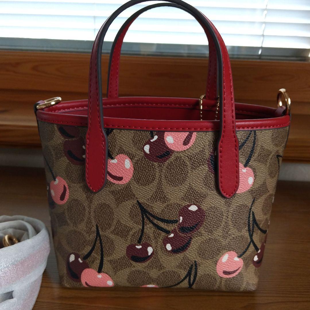 クリーム。COACHチェリー柄トートバッグ、ショルダーストラップ付き。