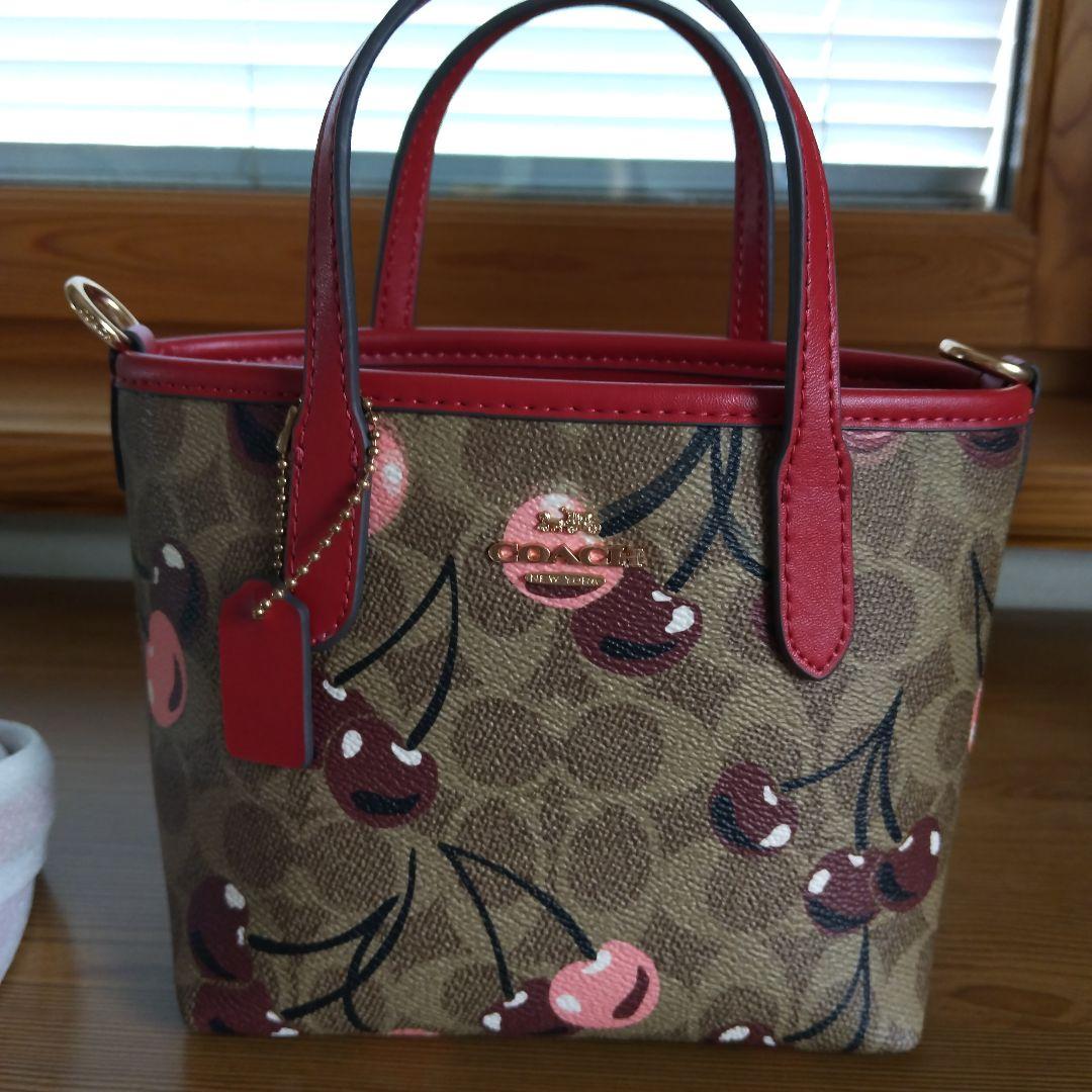クリーム。COACHチェリー柄トートバッグ、ショルダーストラップ付き。