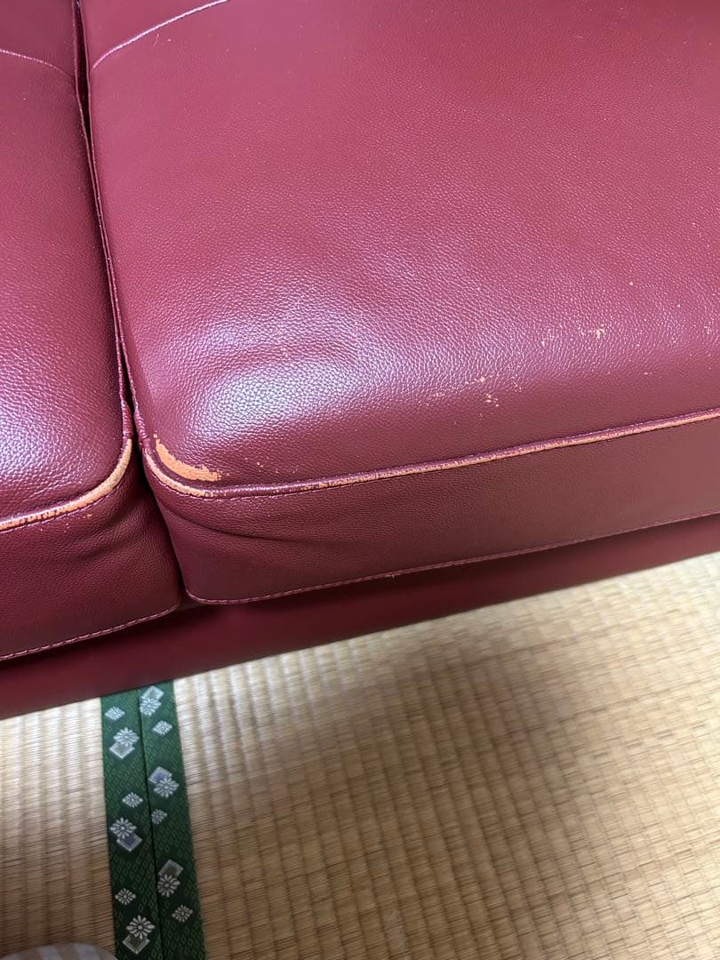 赤い合成皮革の2人掛けソファとオットマン